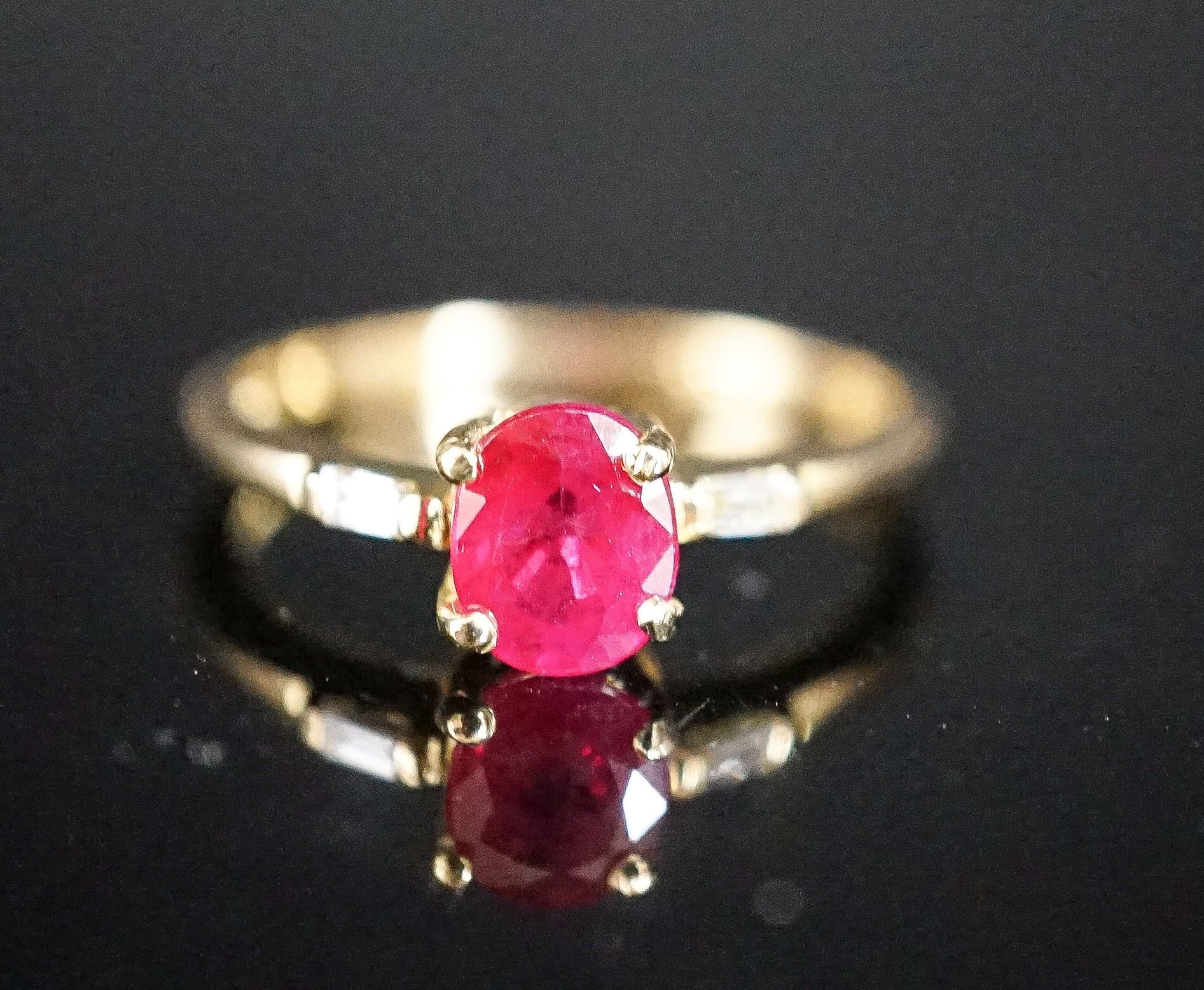 A modern 18ct gold and single stone oval cut ruby ring, with diamond set shoulders, size O, gross weight 2.7 grams.